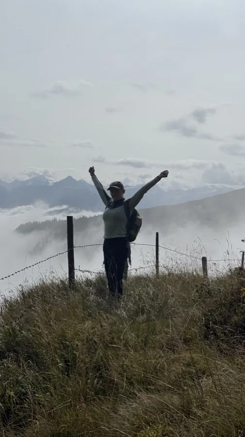 Person auf dem Berggipfel mit erhobenen Armen